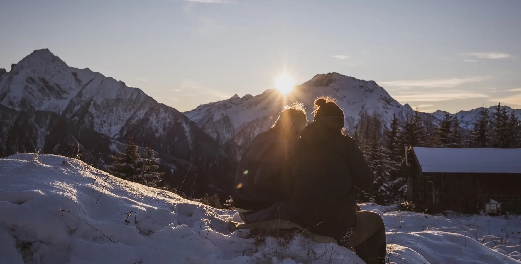 Zwei Menschen betrachten den Sonnenuntergang am Berg